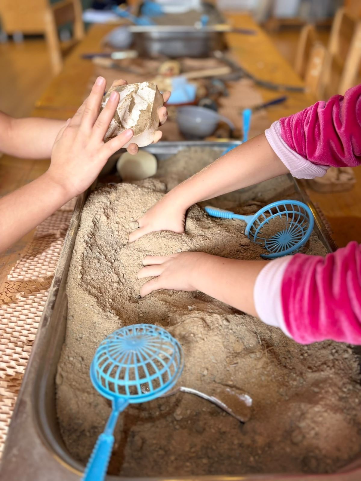 Children exploring with sand at a sensory play table